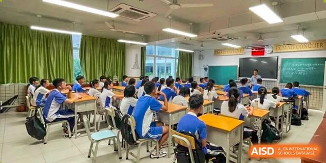 A classroom filled with students in blue and white uniforms sitting at wooden desks during a lesson at Shenzhen Senior High School International Division.