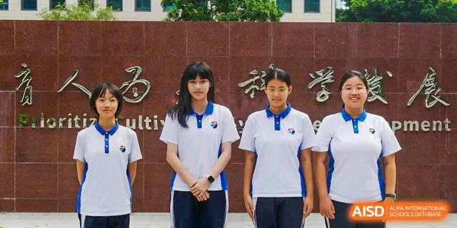 Two female students standing side-by-side outdoors wearing their summer polo uniforms in front of a monument at Shenzhen Senior High School International Division.