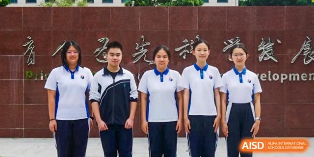 Three students, one in a track jacket and two in polos, posing together in front of a school monument at Shenzhen Senior High School International Division.