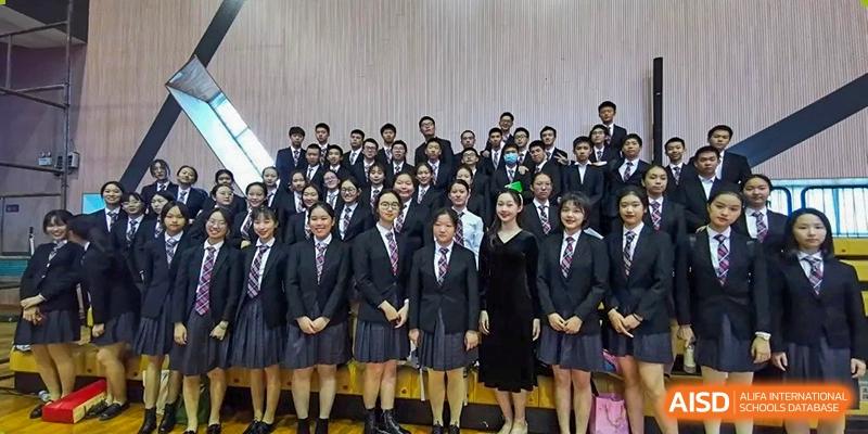 A formal group portrait of students in dark blazers, ties, and grey skirts or trousers posing together at Shenzhen Senior High School International Division.