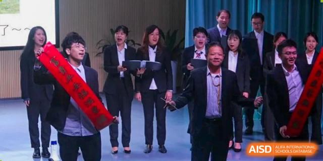 A group of faculty and students in formal professional attire stand on a stage during a ceremony or presentation at Shenzhen Senior High School International Division.