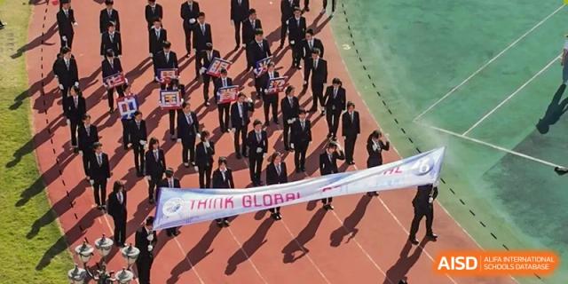 An overhead view of students in suits marching on a red track while carrying a "Think Global" banner at Shenzhen Senior High School International Division.