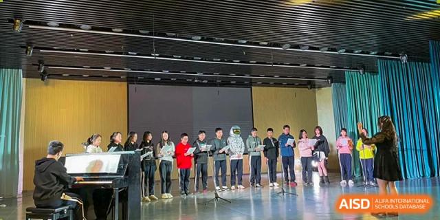 A line of students standing on a stage in a large auditorium during a performance or ceremony at Shenzhen Senior High School International Division.