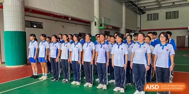 Students in matching blue and white athletic uniforms standing in formation on an indoor court at Shenzhen Senior High School International Division.