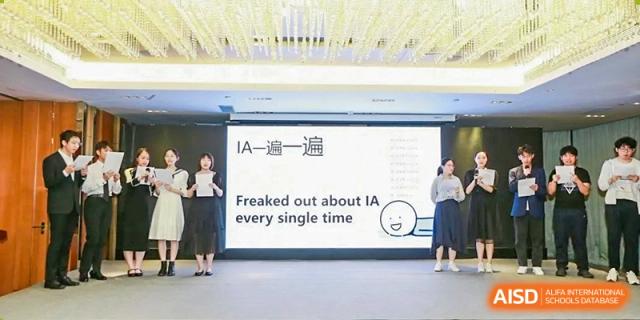 A student giving a presentation on stage next to a slide about IA projects at Shenzhen Senior High School International Division.