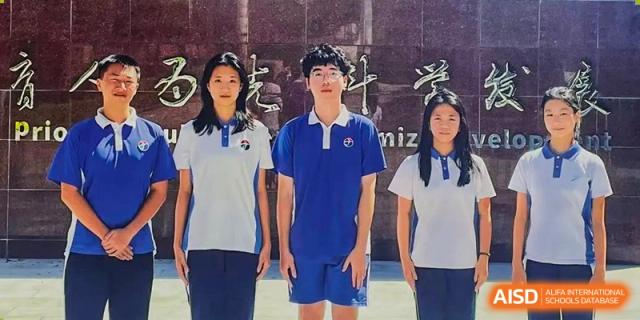 Three students in uniform posing for a portrait in front of the school's stone sign at Shenzhen Senior High School International Division.