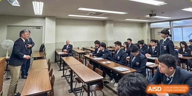 Students in formal blazers sit at long wooden desks during a lecture in a modern classroom at Wuxi Foreign Language School International Curriculum Center.