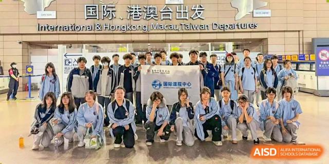 A large group of students gathers for a photo at a "Hong Kong, Macau, Taiwan Departure" gate for Wuxi Foreign Language School International Curriculum Center.