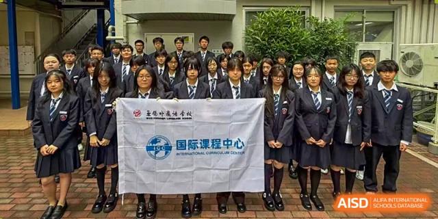 Students in formal navy uniforms stand behind a white school banner for a group portrait at Wuxi Foreign Language School International Curriculum Center.