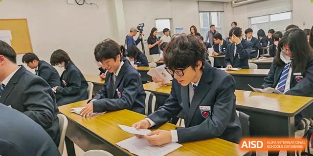 Two students in formal school blazers sit at a desk and review academic papers during a class at Wuxi Foreign Language School International Curriculum Center.