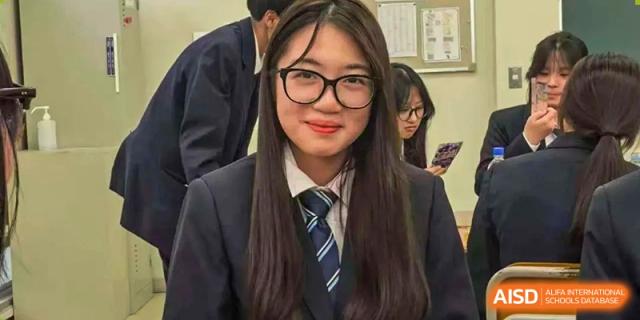 A close-up portrait of a smiling female student wearing glasses and a formal school tie at Wuxi Foreign Language School International Curriculum Center.