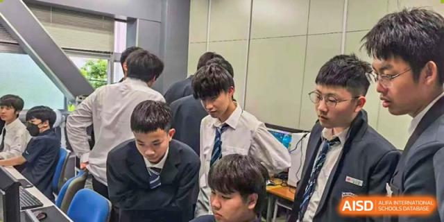 A group of male students in white shirts and ties work together on a computer project at Wuxi Foreign Language School International Curriculum Center.