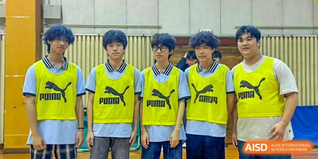 Three male students wearing yellow Puma sports bibs over light blue shirts stand together at Wuxi Foreign Language School International Curriculum Center.