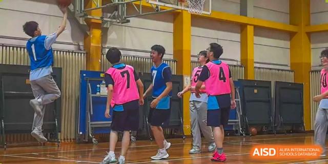Students in pink and blue jerseys interacting during a basketball game at Wuxi Foreign Language School International Curriculum Center.