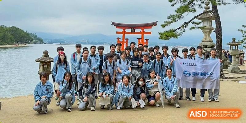 A large group of students poses in front of a traditional red torii gate during a trip for Wuxi Foreign Language School International Curriculum Center.