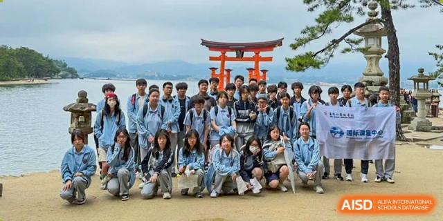 A large group of students poses in front of a traditional red torii gate during a trip for Wuxi Foreign Language School International Curriculum Center.
