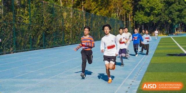Two male students race down an azure blue running track during a track event at Wuxi Foreign Language School International Curriculum Center.