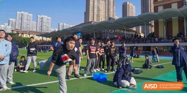 Students in black sports shirts prepare for a competition on a green field at Wuxi Foreign Language School International Curriculum Center.