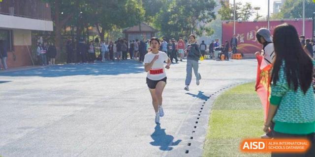 A female student sprints down an outdoor track during a school athletics competition at Wuxi Foreign Language School International Curriculum Center.
