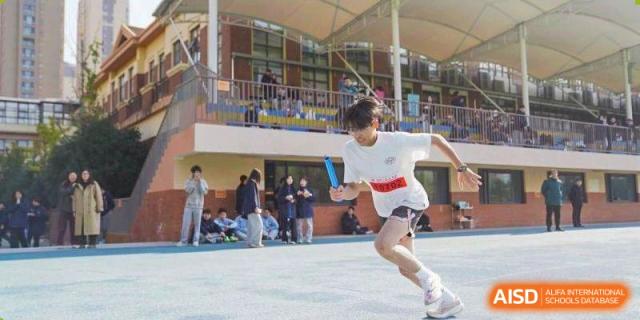 A student athlete sprints with a baton during a relay competition at Wuxi Foreign Language School International Curriculum Center.