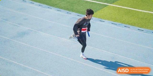 A runner in a black athletic suit competes on a blue running track at Wuxi Foreign Language School International Curriculum Center.