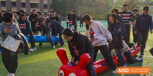 Students laugh while competing in an inflatable animal race on a field at Wuxi Foreign Language School International Curriculum Center.