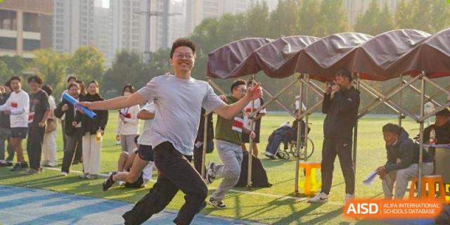 A student athlete smiles while running a race on an outdoor sports field at Wuxi Foreign Language School International Curriculum Center.