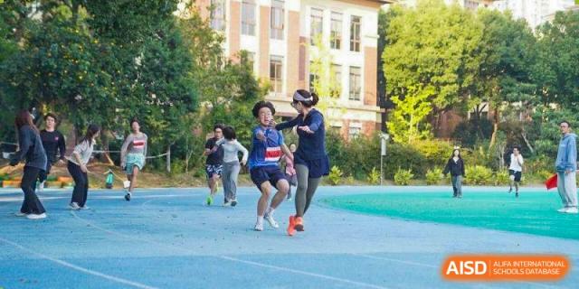 Runners competing in a sprint on a blue track with school buildings in the background at Wuxi Foreign Language School International Curriculum Center.