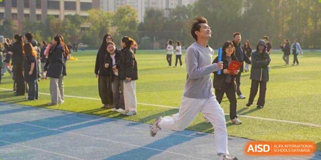A male student sprints toward the finish line during a track event on a sunny day at Wuxi Foreign Language School International Curriculum Center.