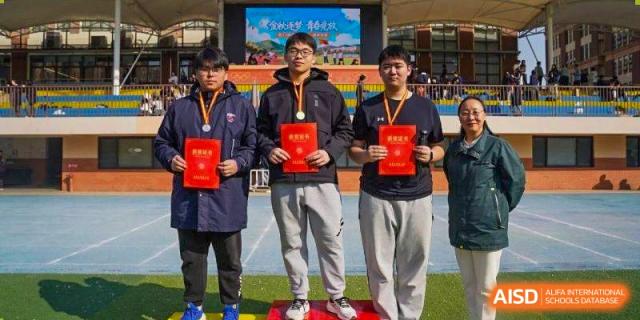 Three male students stand on a podium holding red award certificates after a competition at Wuxi Foreign Language School International Curriculum Center.