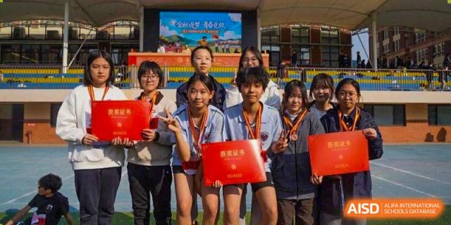 A group of students smiles while displaying their red award certificates after an event at Wuxi Foreign Language School International Curriculum Center.