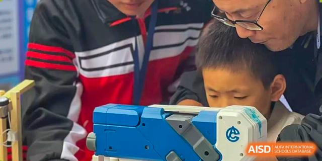 A close-up view of a student operating a blue and grey electronic device during a technical workshop or science activity at Wenzhou Foreign Language School.