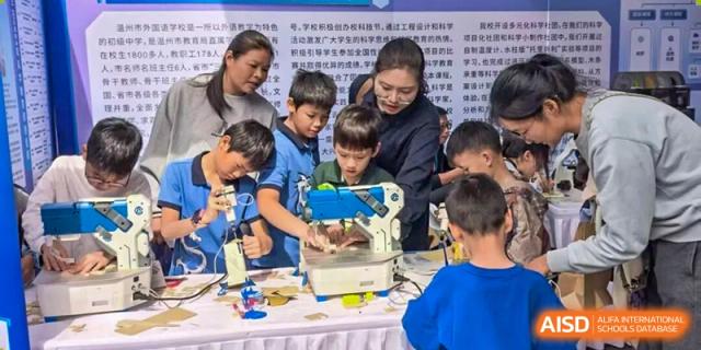 An instructor guides young students as they use a specialized crafting machine during an interactive science and technology fair at Wenzhou Foreign Language School.