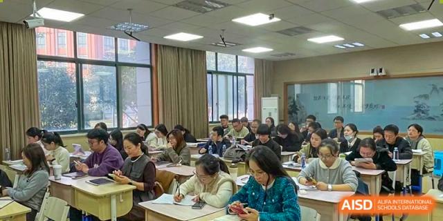 Adult students taking notes and listening attentively during a lecture in a large classroom at Wenzhou Foreign Language School.