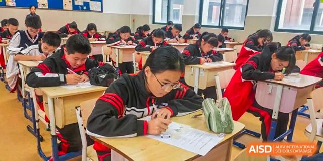 Students in matching black and red tracksuits sit at individual desks while taking a test at Wenzhou Foreign Language School.