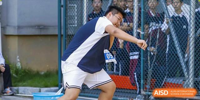 A young male student wearing a sports uniform and bib number 09 prepares for a shot put throw during a field event at Wenzhou Foreign Language School.