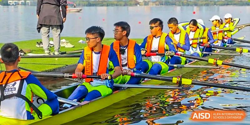 A group of students wearing orange life jackets rowing a boat together on a body of water at Wenzhou Foreign Language School.