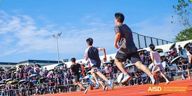 Several male students sprinting toward the finish line during a competitive track race at Wenzhou Foreign Language School.
