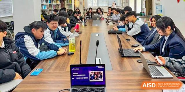 A large group of students and faculty members participate in a formal business meeting around a long conference table at XuZhou No.3 Middle School.