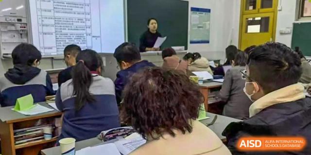 A teacher stands at the front of a classroom while students take notes during a standard academic lesson at XuZhou No.3 Middle School.