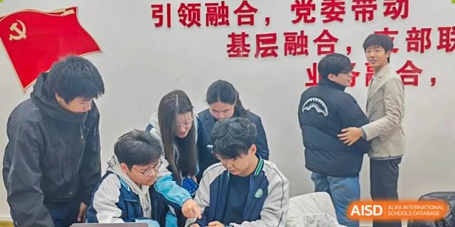 A group of students huddles together to work on a laptop during a collaborative project in class at XuZhou No.3 Middle School.