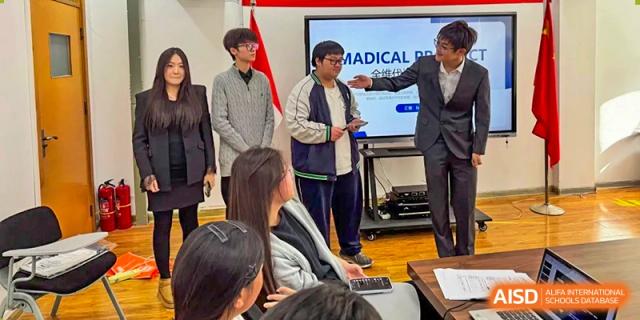 A student stands to present a "Medical" project to his peers and teacher in a modern meeting room at XuZhou No.3 Middle School.