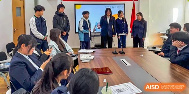 Students gather around a table to watch a digital presentation during an interactive group session at XuZhou No.3 Middle School.