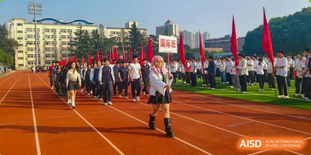 A student dressed in a costume leads a parade of students across a red running track during an outdoor festival at XuZhou No.3 Middle School.