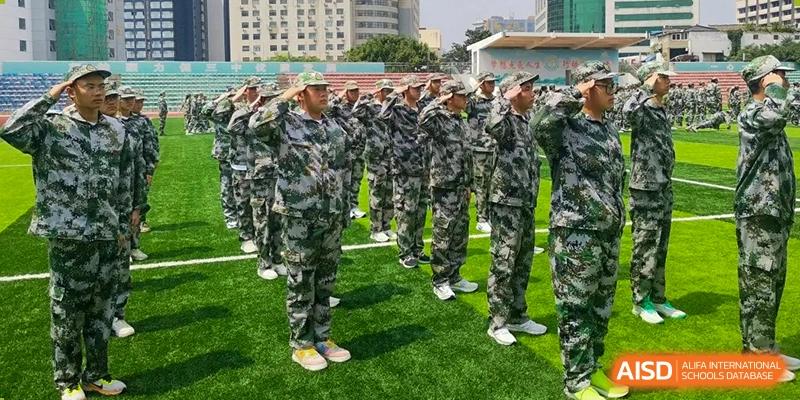 Rows of students in camouflage attire stand at attention and salute during a military training exercise at XuZhou No.3 Middle School.