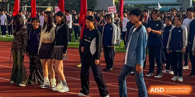 Students in casual athletic wear walk and stand together on the school's red outdoor running track during the day at XuZhou No.3 Middle School.