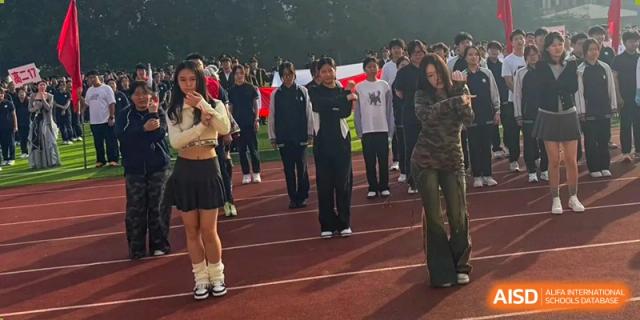 Students participate in a group activity or exercise while standing in formation on the outdoor athletic track at XuZhou No.3 Middle School.
