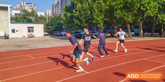 Three male students compete in a fast-paced sprint on the red running track under the bright afternoon sun at XuZhou No.3 Middle School.