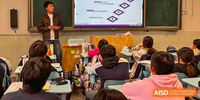 Students sit at their desks in a classroom facing a digital screen displaying an educational presentation at XuZhou No.3 Middle School.