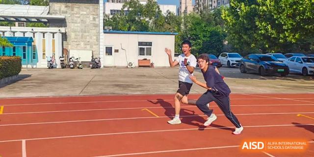 A student athlete in a white shirt and black shorts sprints toward the finish line during an outdoor track race at XuZhou No.3 Middle School.